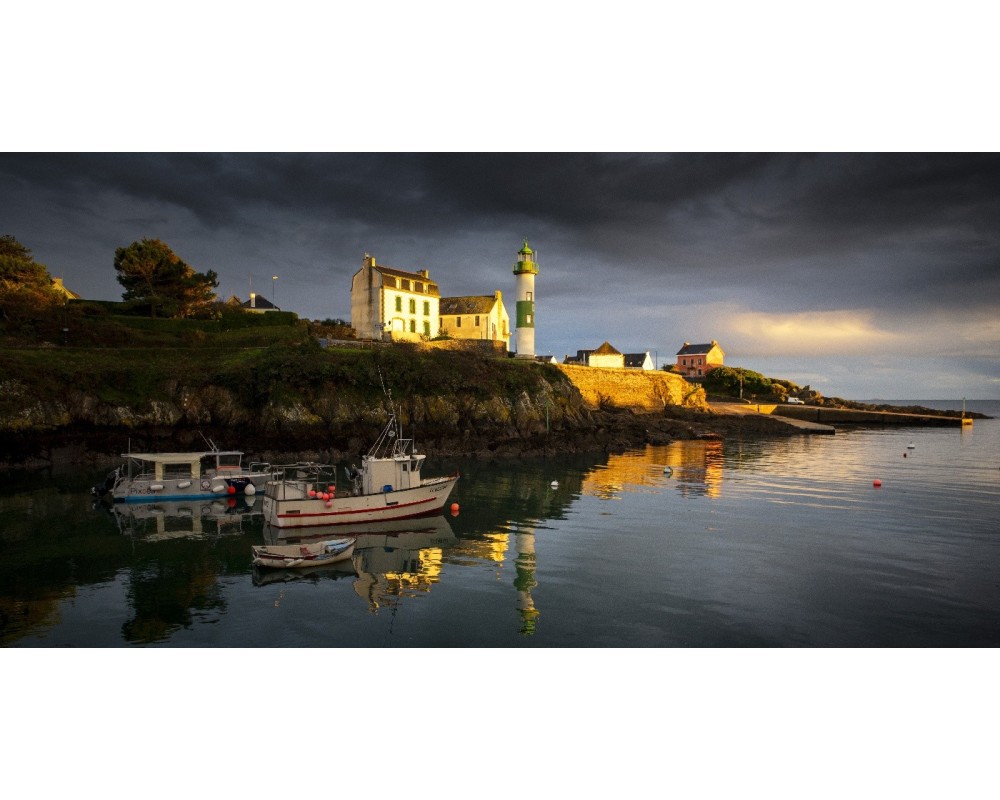 Lumière dorée sur les maisons de Doëlan, ciel sombre