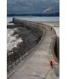 Saint-Malo — digue courbe et mouette en vol sous ciel de tempête