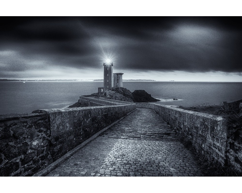 Phare du Petit Minou allumé sous un ciel d'orage — noir et blanc