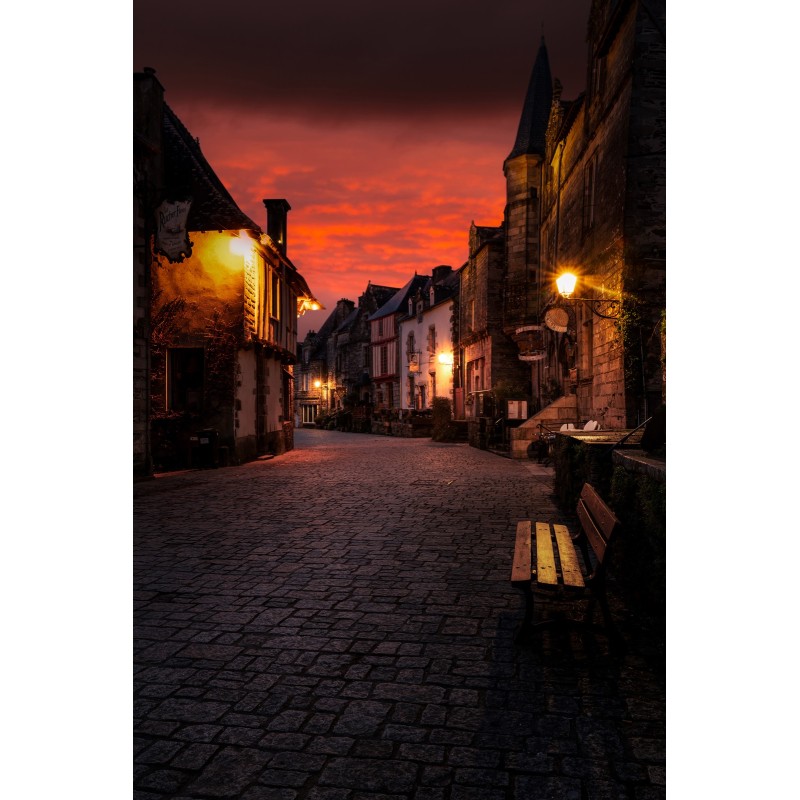 Rochefort-en-Terre, rue pavée sous un ciel de feu